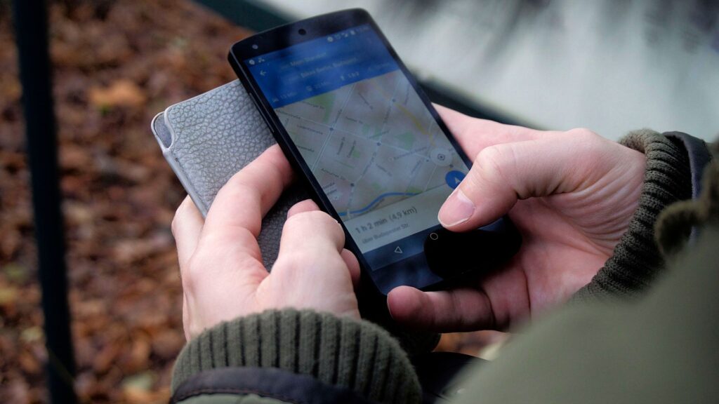 Hände halten ein Smartphone mit geöffneter Kartenanwendung