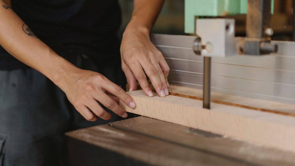 Schreiner sägt in der Werkstatt ein Holzbrett an der Bandsäge zu
