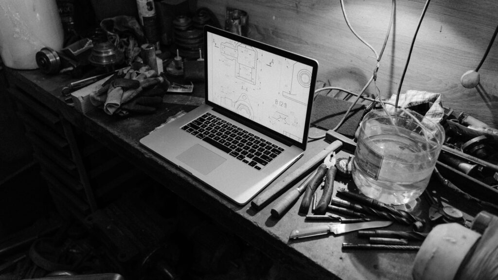 Laptop mit Bauplänen auf einer Werkbank in einer Werkstatt