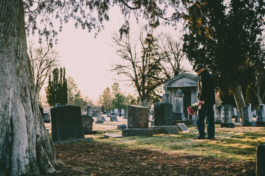 Person mit Blumen auf einem ruhigen Friedhof