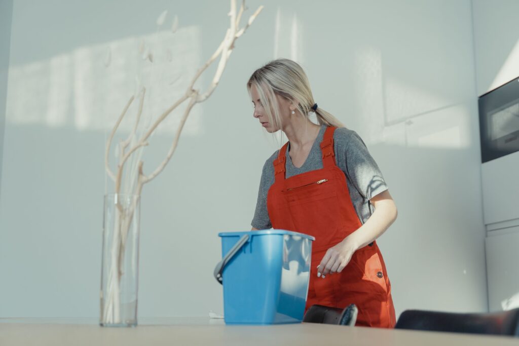 Reinigungskraft in Arbeitskleidung wischt in einem Gebäude